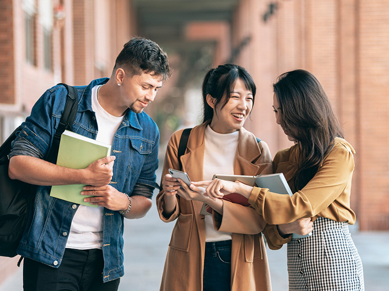 University students on campus, holding books and laughing